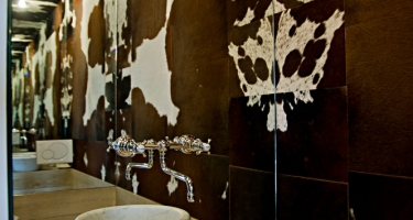 Powder room with cowhide walls, ceiling and mirror